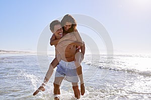 Man Giving Woman Piggyback On Summer Beach Vacation