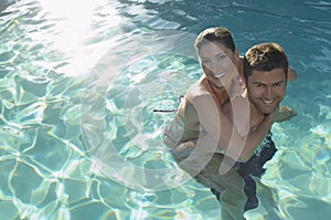 Man Giving Woman Piggyback In Swimming Pool