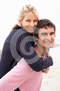 Man Giving Woman Piggyback On Winter Beach photo