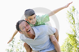 Man giving young boy piggyback ride smiling