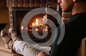 Man with glass of wine near fireplace at home