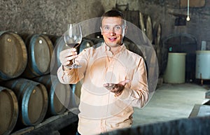 Man with glass of wine in winery cellar