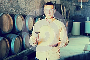 Man with glass of wine in winery cellar