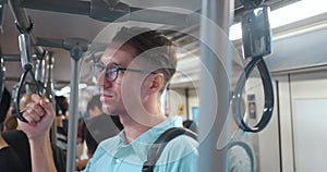 Man glasses, backpack back, grips handrail subway, vivid portrayal everyday public transport usage, highlighting