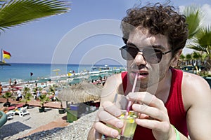 Man in glasses drink cocktail Mojito on beach