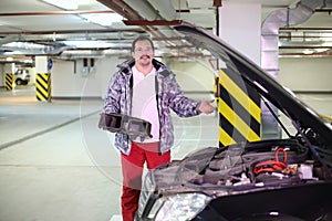 Man in glasses with ductwork near open hood of photo