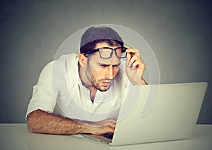 Man with glasses having eyesight problems confused with laptop