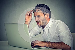 Man with glasses having eyesight problems confused with laptop software