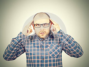 Man with glasses holding his head with his hands.