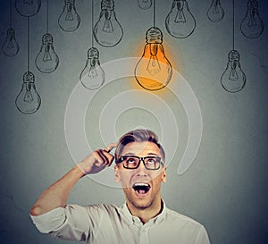 Man in glasses looking up at light bulb has solution