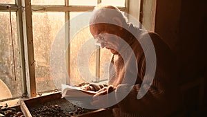 man glasses picks up old book in dust read in house window