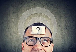 Man in glasses with question mark looking up