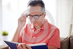 Man in glasses reading book at home