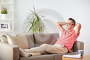 Man in glasses relaxing on sofa at home
