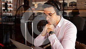 man with glasses resting his elbows on the table in front of the computer