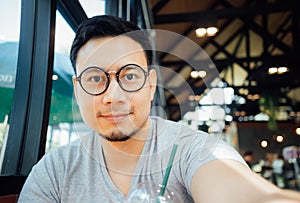 Man with glasses selfy himself drink coffee in the cafe