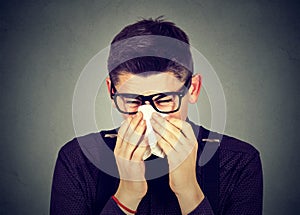 Man in glasses sneezing blowing runny nose photo