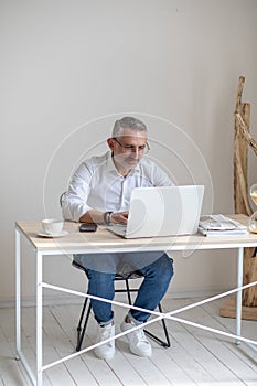 Man with glasses typing on laptop at table