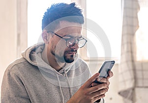 A man with glasses uses a smartphone, copy space.