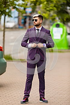 Man in glasses and violet luxery three-piece suit, bow tie posing on the street