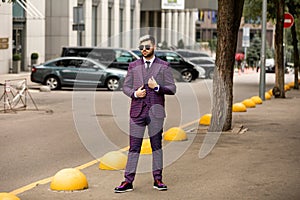 Man in glasses and violet luxery three-piece suit, bow tie posing on the street