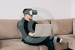 The man with glasses of virtual reality sitting on couch while working from home office