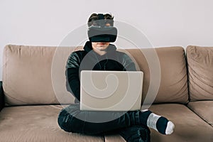 The man with glasses of virtual reality sitting on couch while working from home office