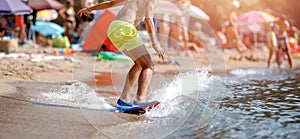 Man glides on surf waves near shore, sandy beach sunset summer