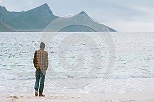 Man globetrotter walking on Haukland beach in Norway Lofoten islands adventure travel lifestyle photo