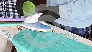 A man in gloves adds water to an iron. On the ironing board is a stack of men`s shirts for ironing. Close-up shot