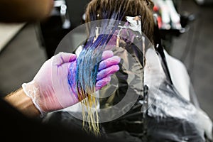 Man in gloves is dying long blue hair colorfull. Beauty salon, Barber.