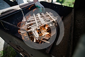 A man in gloves kindles fire from stacked wood. Preparation for a barbecue