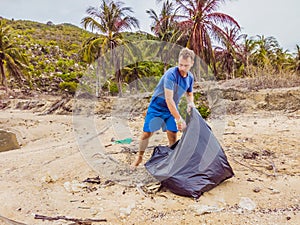 Man in gloves pick up plastic bags that pollute sea. Problem of spilled rubbish trash garbage on the beach sand caused