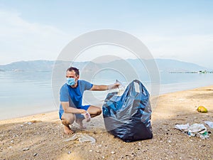 Man in gloves pick up plastic bags that pollute sea. Problem of spilled rubbish trash garbage on the beach sand caused