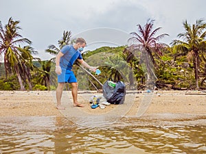 Man in gloves pick up plastic bags that pollute sea. Problem of spilled rubbish trash garbage on the beach sand caused