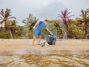 Man in gloves pick up plastic bags that pollute sea. Problem of spilled rubbish trash garbage on the beach sand caused