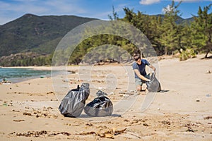 Man in gloves pick up plastic bags that pollute sea. Problem of spilled rubbish trash garbage on the beach sand caused photo