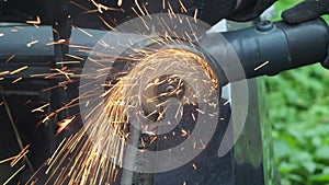 a man in gloves saws metal with a cutting disc. angle grinder. working with metal. fiery bright splashes. car repair