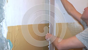 A man glues a decorative PVC panel to the wall in foam glue