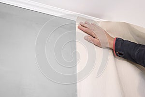 A man glues wallpaper in the room. Repair, construction and home concept
