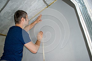 A man glues wallpaper in a room. Wallpapering in apartment.