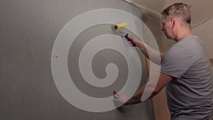 A man glues Wallpaper to the wall.