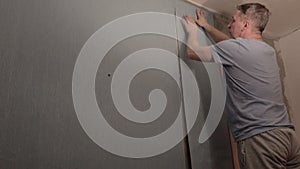 A man glues Wallpaper to the wall.