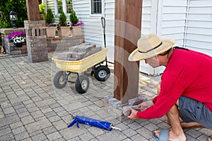 Man gluing bricks to form a pillar on a patio