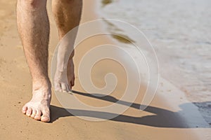 Man goes barefoot on the sand along the shore