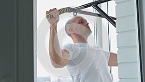 Man goes in for sports doing pull-up exercises on horizontal bar at his home