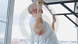 Man goes in for sports doing pull-up exercises on horizontal bar at his home