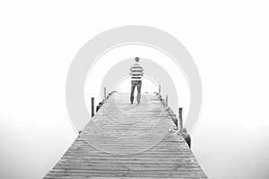 A man goes on the wooden pier in high key. Black and white