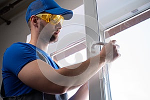 Man in goggles checks satisfactory state of window handle