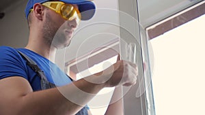 Man in goggles checks satisfactory state of window handle